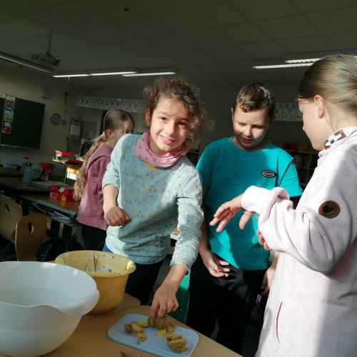 Drei Kinder holen sich Kartoffelscheiben mit Kräuteraufstrich.
